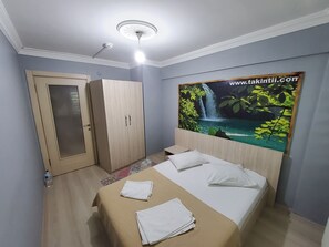 Un dormitorio con cama, armario, puerta y pared con un cartel.