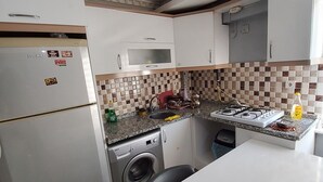 Ett kompakt kök med en inbyggd tvättmaskin, en mikrovågsugn och en gasspis.
