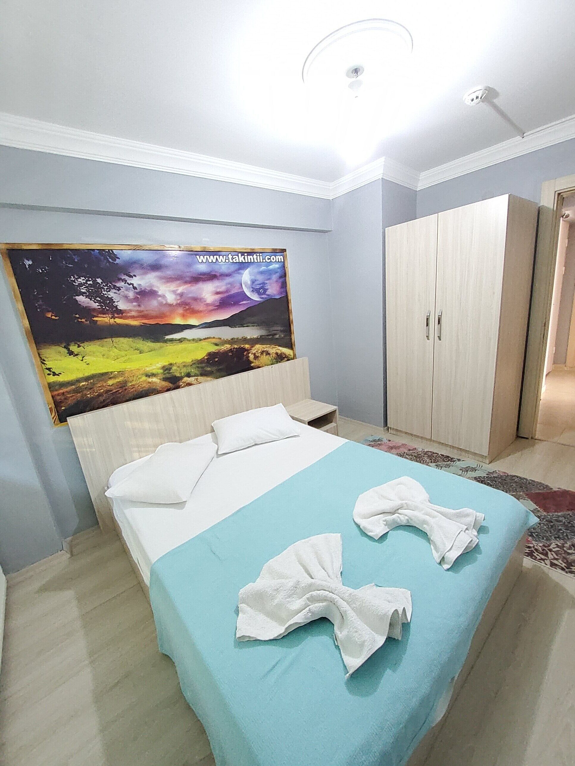 A bedroom with a bed, a wardrobe, and a painting on the wall.