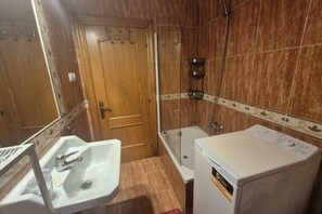 Un baño con lavamanos, bañera y lavadora.