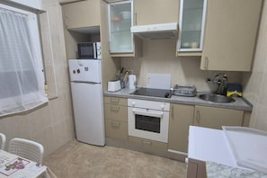 Cocina compacta equipada con refrigerador, horno, microondas y lavaplatos.