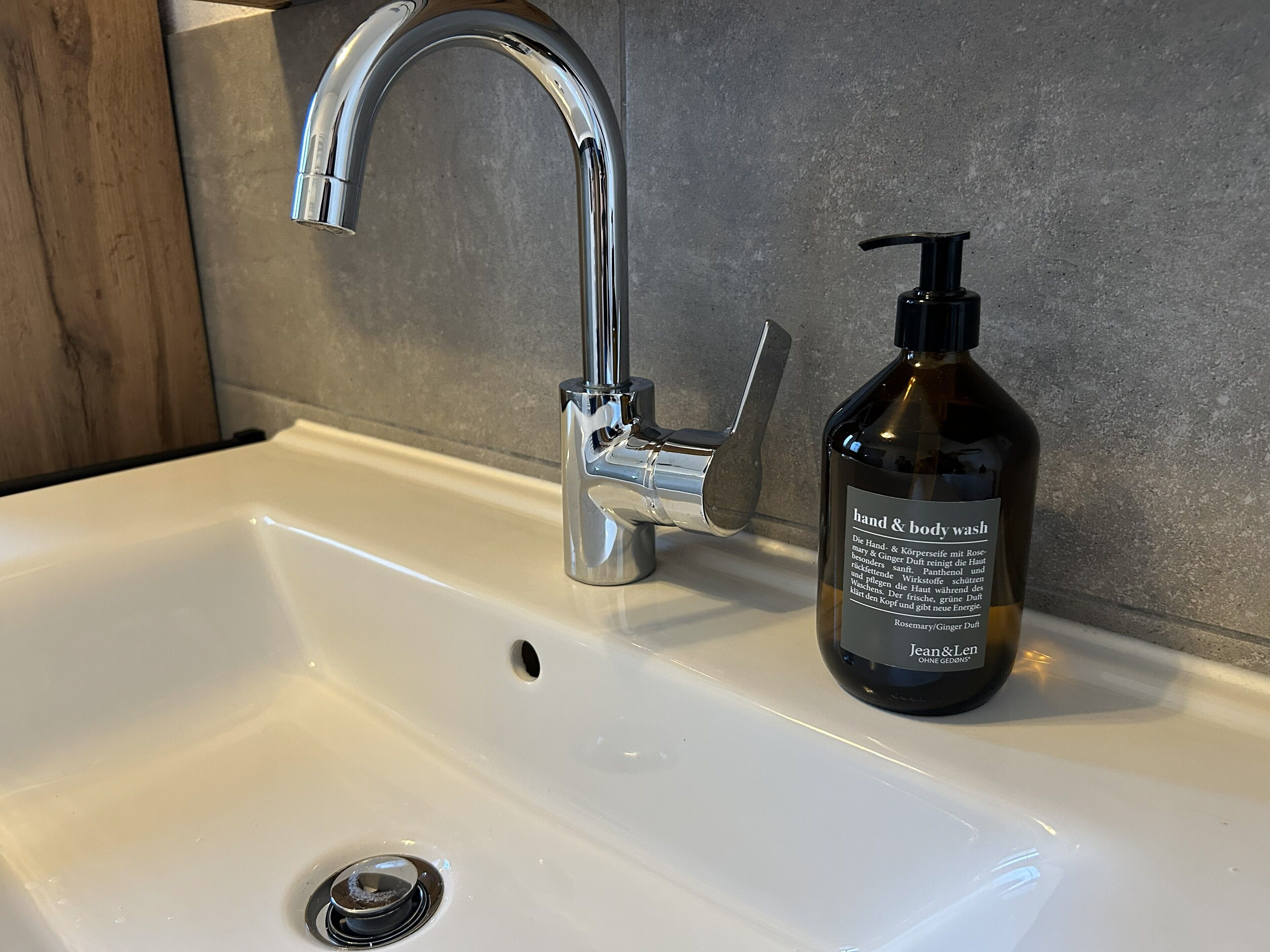 Ein Waschbecken mit chromfarbenem Wasserhahn und einer Flasche Hand- und Körperwaschgel.