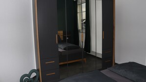 Un dormitorio con cama, armario y espejo.