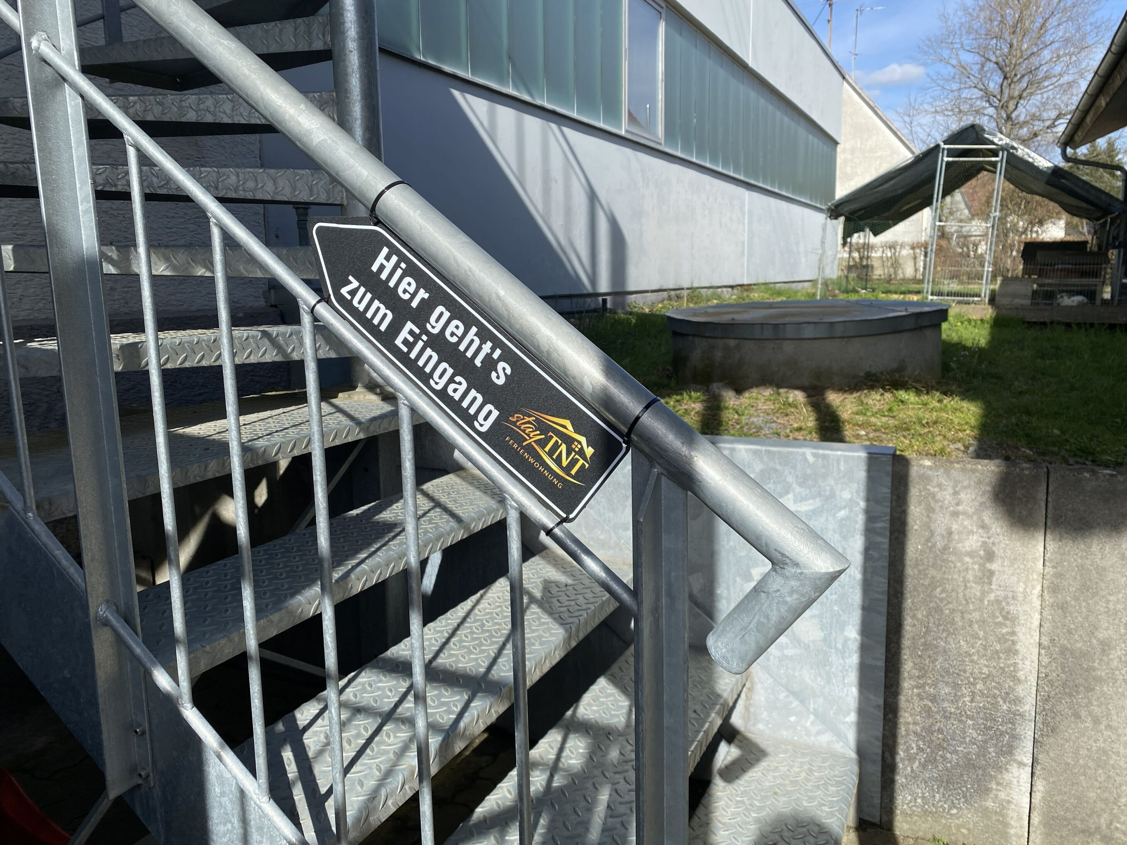 Eine Treppe mit einem Schild, auf dem 'Hier geht's zum Eingang' steht, und dem Logo von 'stayINT'.