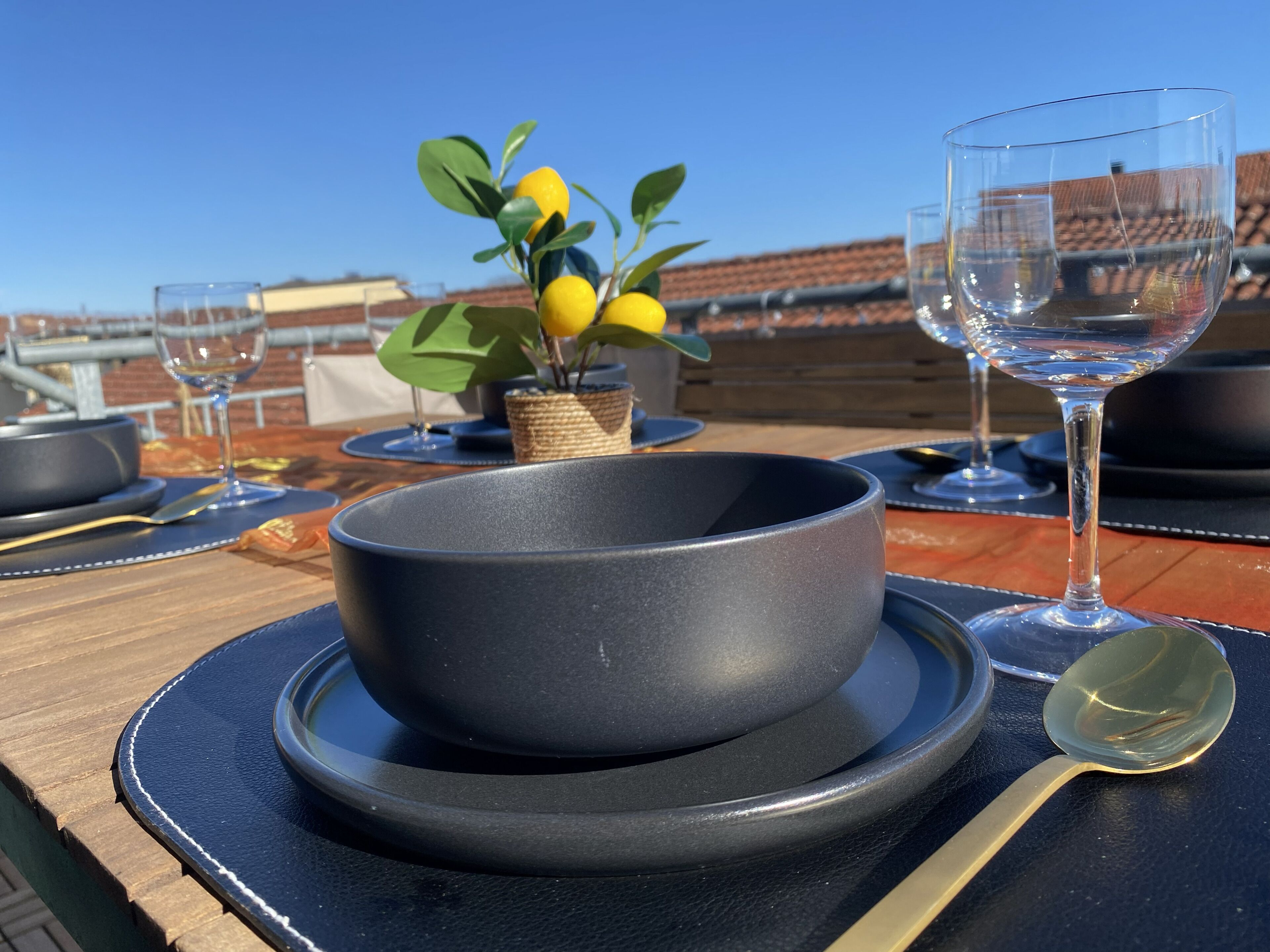 Un tavolo da pranzo con una ciotola, un bicchiere e un cucchiaio, su sfondo di cielo sereno.