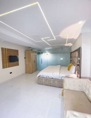 Un dormitorio moderno con cama, armario y televisor en la pared.