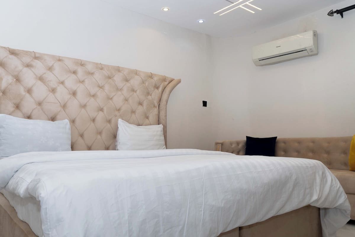 Un dormitorio con una cama grande, un sofá y un equipo de aire acondicionado en la pared.