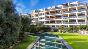 A modern multi-story building with balconies, a swimming pool, and well-maintained greenery. - Charming T1 in residence with swimming pool (Porto-Vecchio)