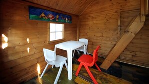 A wooden cabin interior with a dining table and chairs, a window, and a painting on the wall. - Villa CYN-pool, billiards, piano and miniature golf (Santo Stefano di Camastra)