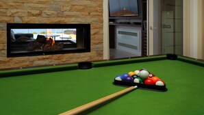 A pool table with balls and a pool cue, a stone wall, and a television screen displaying a fire. - Villa CYN-pool, billiards, piano and miniature golf (Santo Stefano di Camastra)
