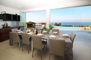 A dining area with a table set for six, overlooking a pool and the ocean. - Villa CYN-pool, billiards, piano and miniature golf (Santo Stefano di Camastra)