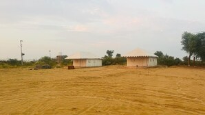 A desert landscape with two tents and a water tower. - Shree Karni Hotel & Restaurant (Bikaner)