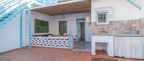 Una cocina con salpicadero de azulejos, encimera blanca y ventana con detalles azules.