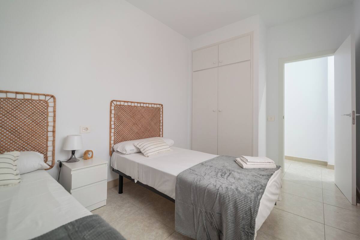 A bedroom with two beds, a wardrobe, and a nightstand.