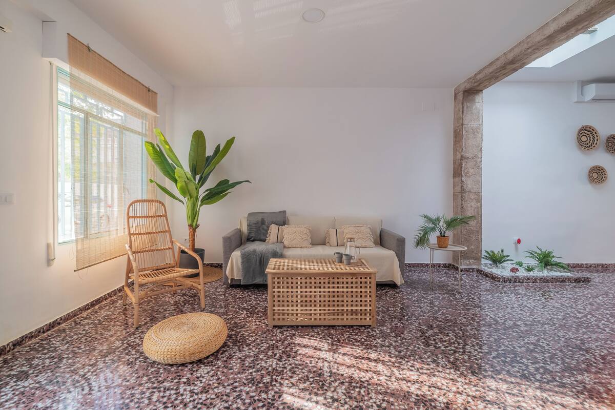 A room with a sofa, a chair, a coffee table, a potted plant, and a decorative wall.