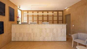 A reception desk with a tiled counter, a seating area with a chair, and a wall-mounted security camera.