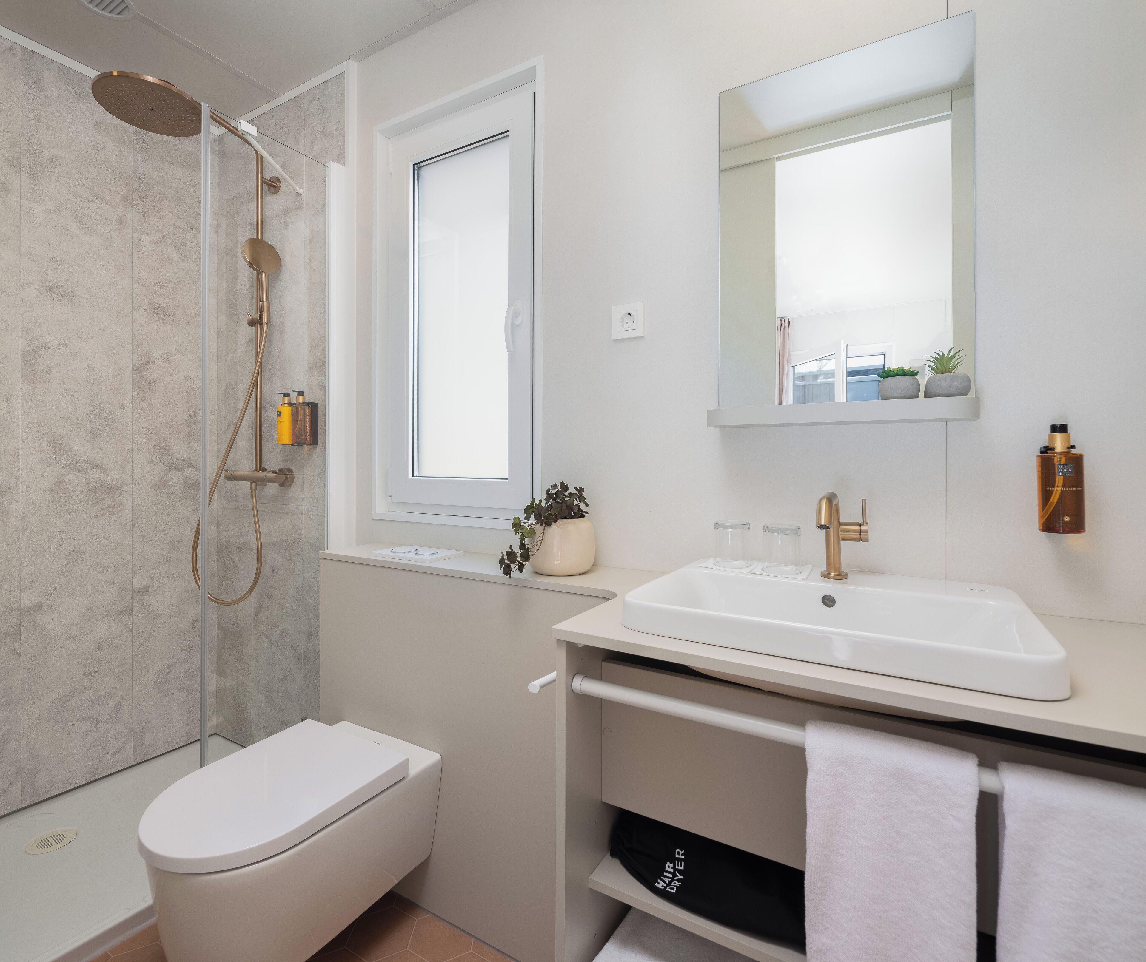 A modern bathroom with a shower, toilet, sink, and a mirror.