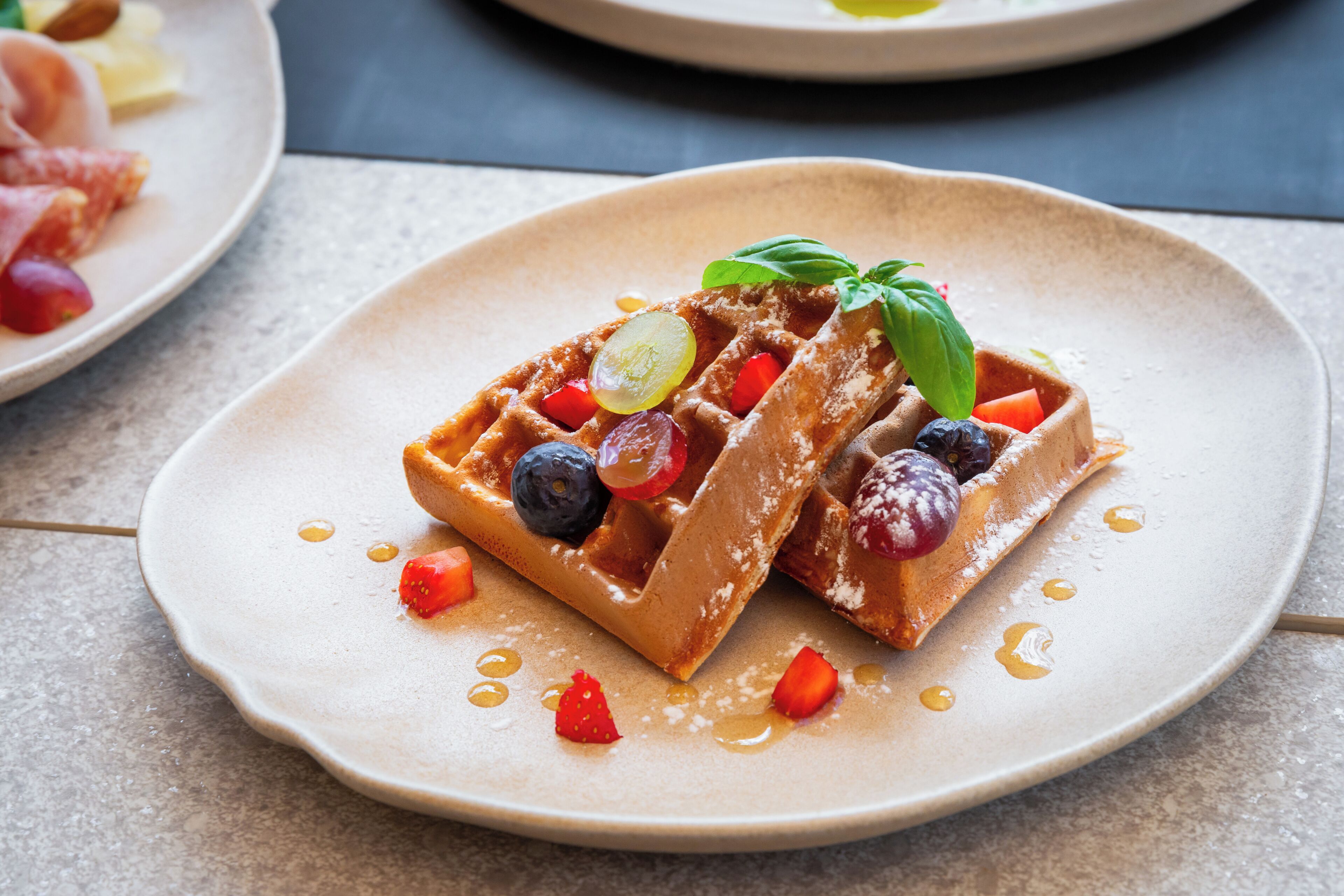 Un plato de waffles cubiertos de fruta y almíbar.
