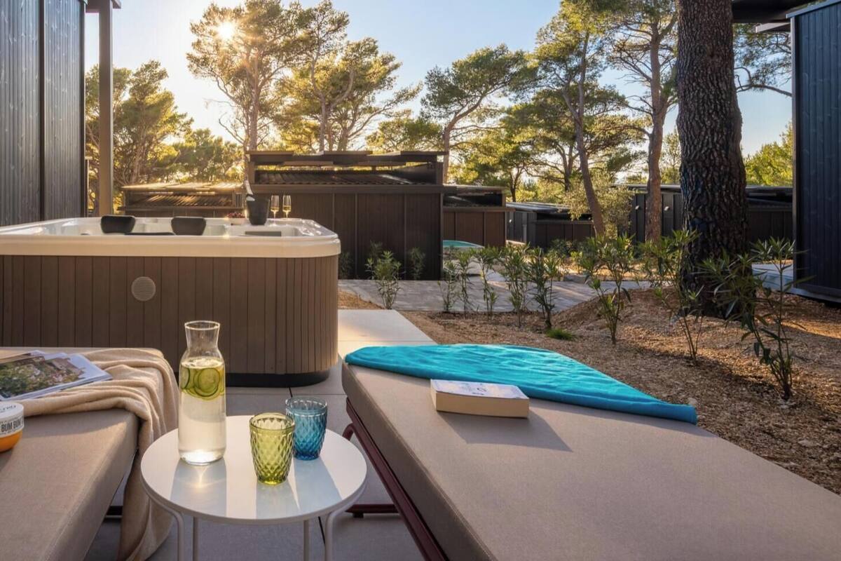 An outdoor seating area with a hot tub, lounge chairs, and a small table with drinks and a book.