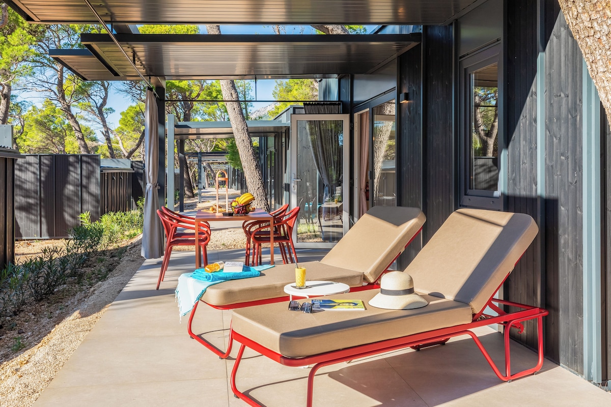 A modern outdoor lounge area with two sun loungers, a table, and chairs.
