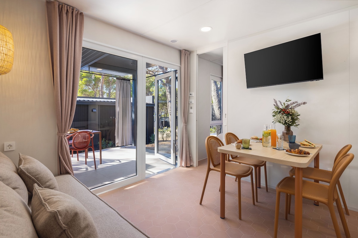 A modern living room with a sofa, dining table, chairs, and a TV mounted on the wall.