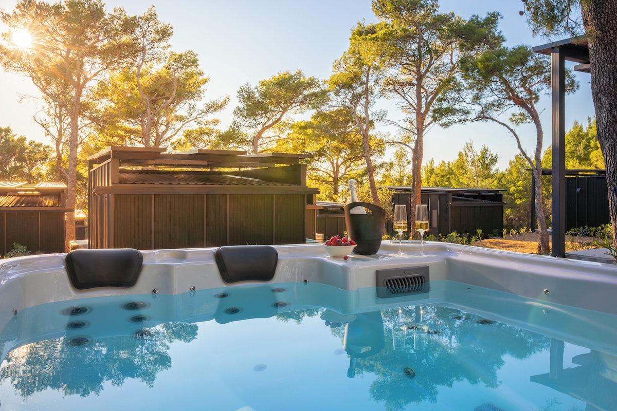 A hot tub with three seating areas, surrounded by trees and a wooden deck.