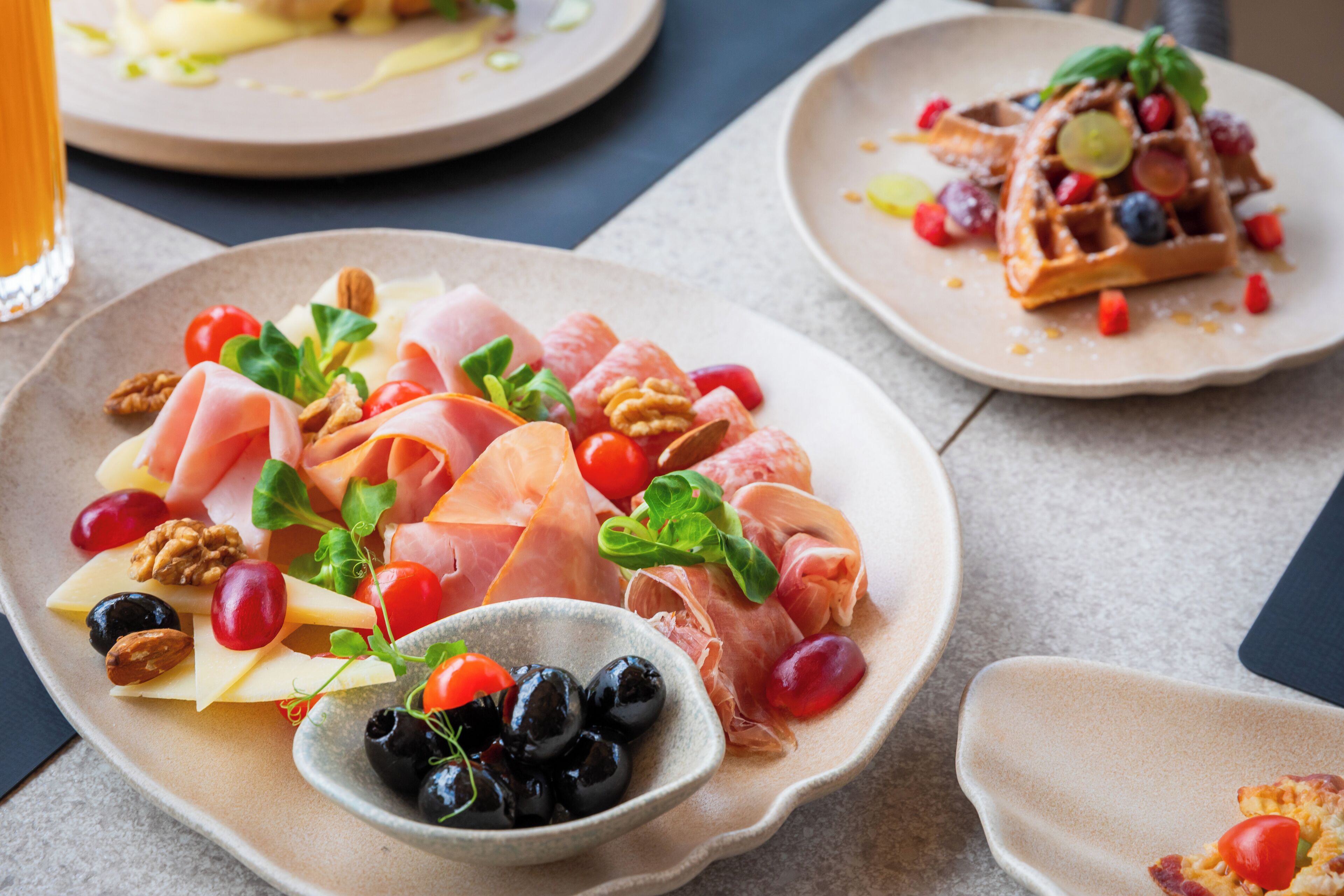 Un plato con quesos variados, frutas y frutos secos.