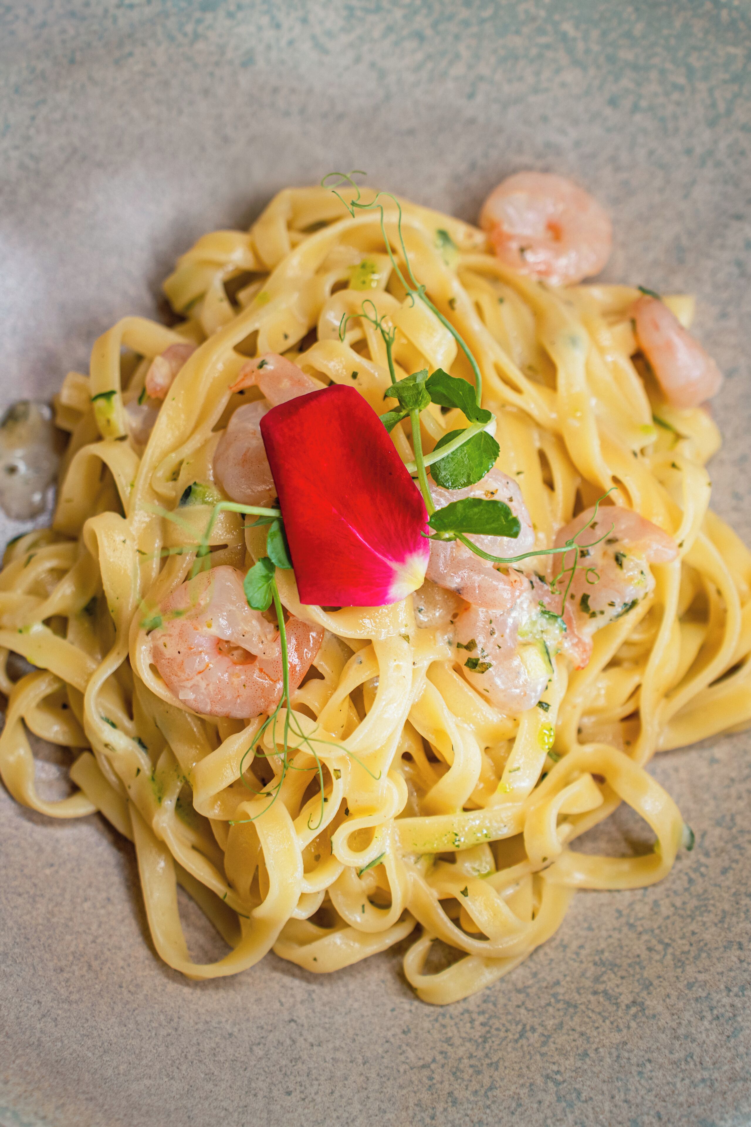A plate of pasta with shrimp and garnishes.