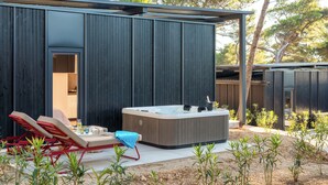 A modern outdoor hot tub area with two lounge chairs, a wooden deck, and a covered seating area. - Pinadria Camping Resort (Baška Voda)