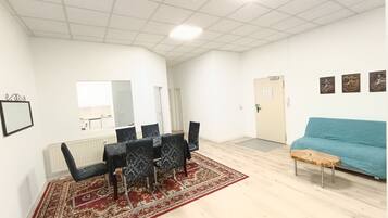 A spacious room with a dining area, a sofa, and a door.