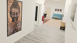 Een hal met een groot Boeddha-schilderij, een blauwe bank en een rieten mand.