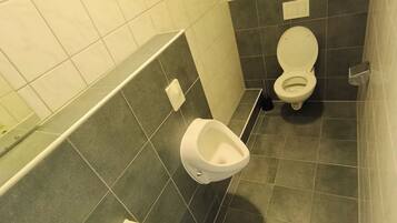 Ein Badezimmer mit Toilette, Urinal und Waschbecken.