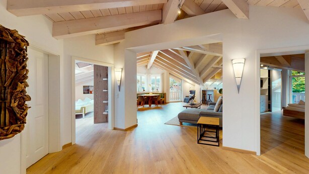 Ein großzügiges Loft mit hohen Decken, freiliegenden Balken und einem geräumigen Wohnbereich mit Sofa und Couchtisch.