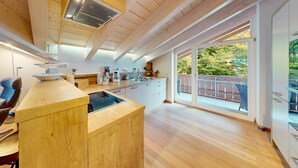 Eine moderne Küche mit Holzschränken, einer zentralen Kochinsel und einem großen Schiebeglastür zum Balkon.