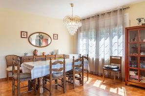 A dining room with a wooden table, chairs, a chandelier, and a cabinet with glass doors.