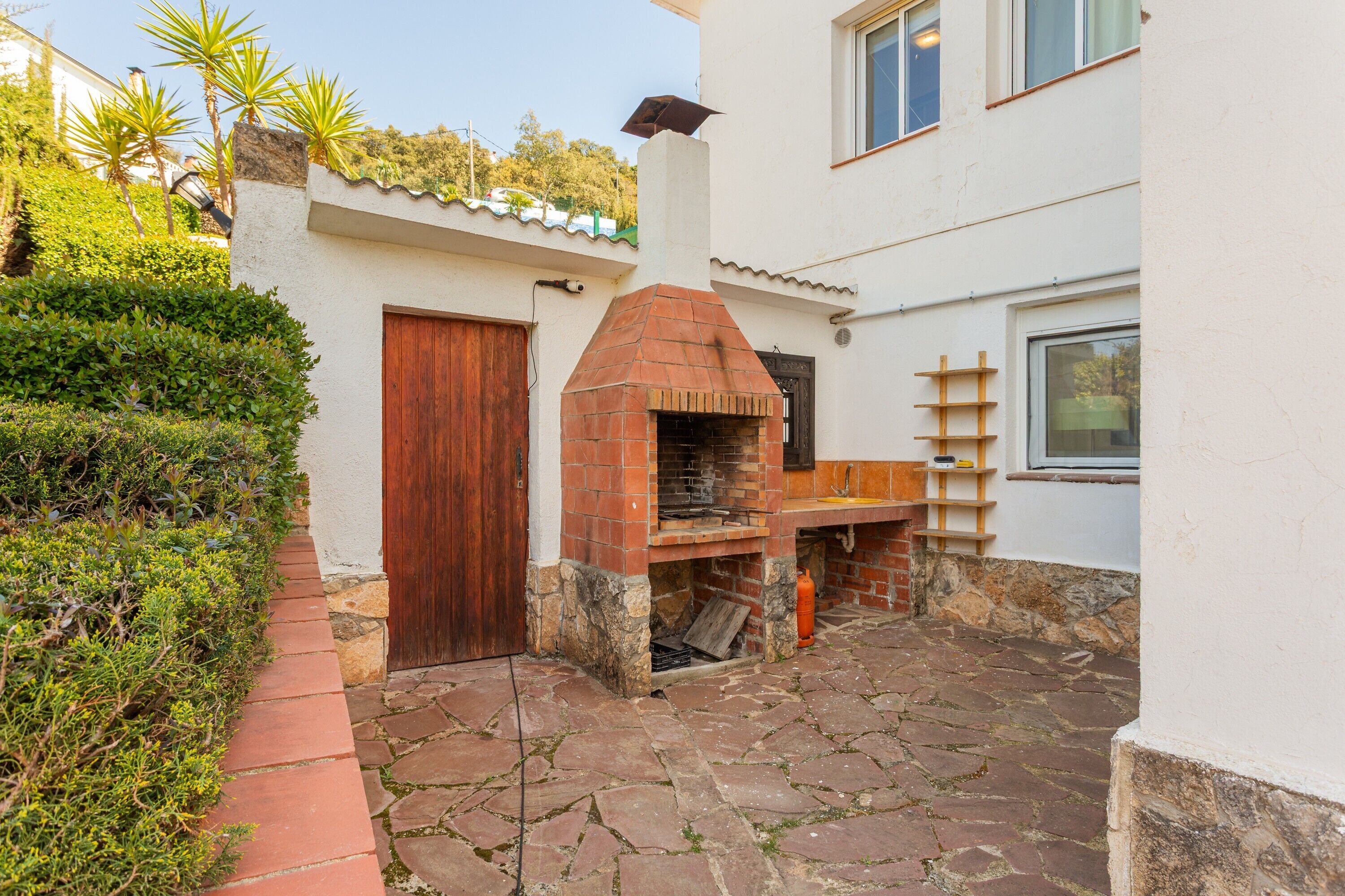 A brick outdoor oven, a wooden door, and a stone-paved patio.