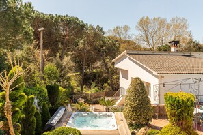 Ein Wohngebiet mit Whirlpool, Holzterrasse und einem Haus mit Ziegeldach.