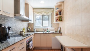 Une cuisine dotée de plans de travail en granit, d’un lave-vaisselle et d’une fenêtre offrant une vue agréable.