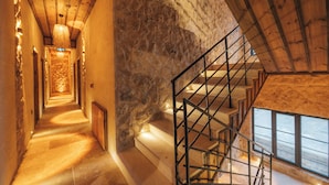 A stone-walled hallway with wooden beams and a staircase with metal railings. - Dream of Stones Cappadocia (Nevşehir)