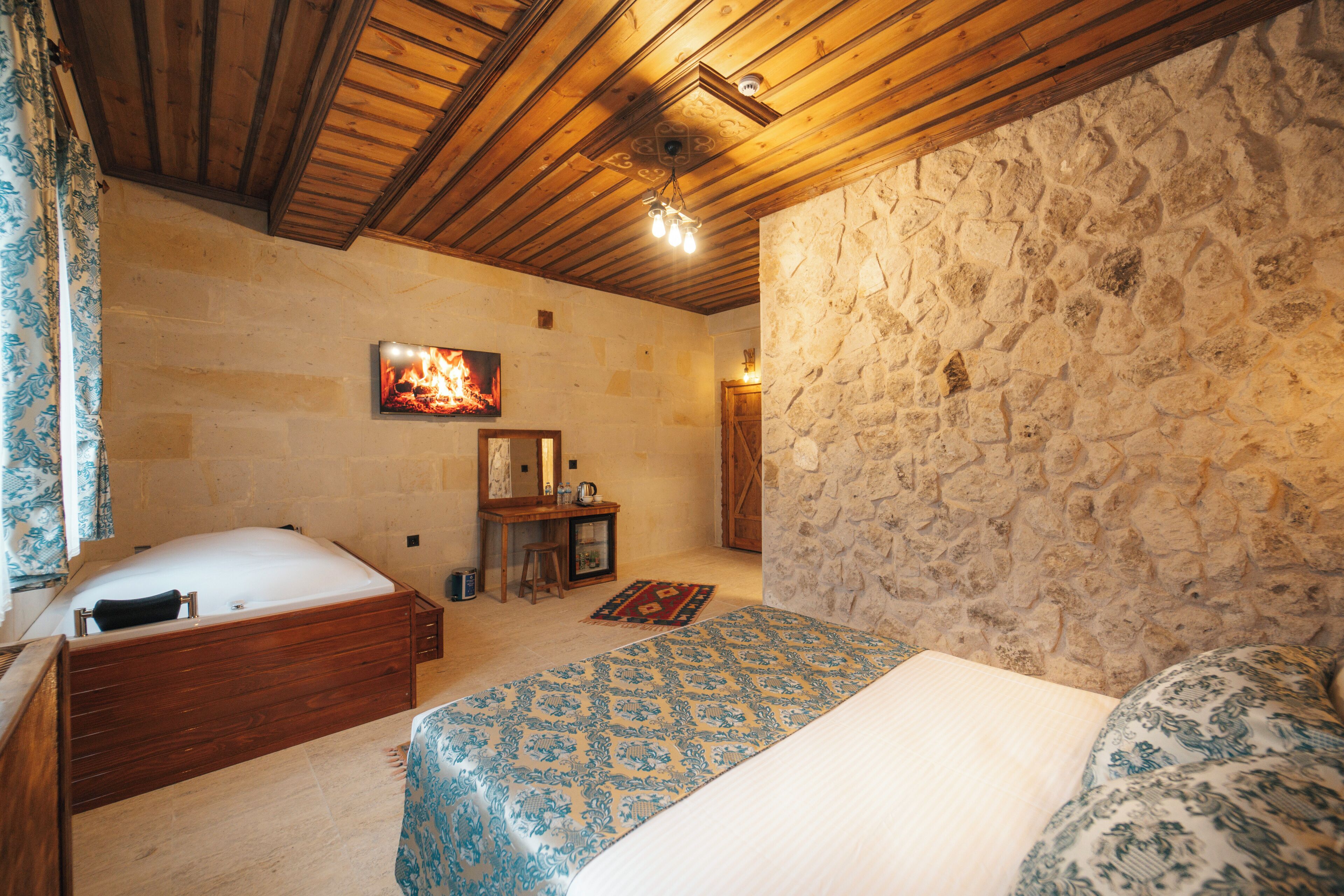 Een slaapkamer met een stenen muur, houten plafond en een bed met behang.