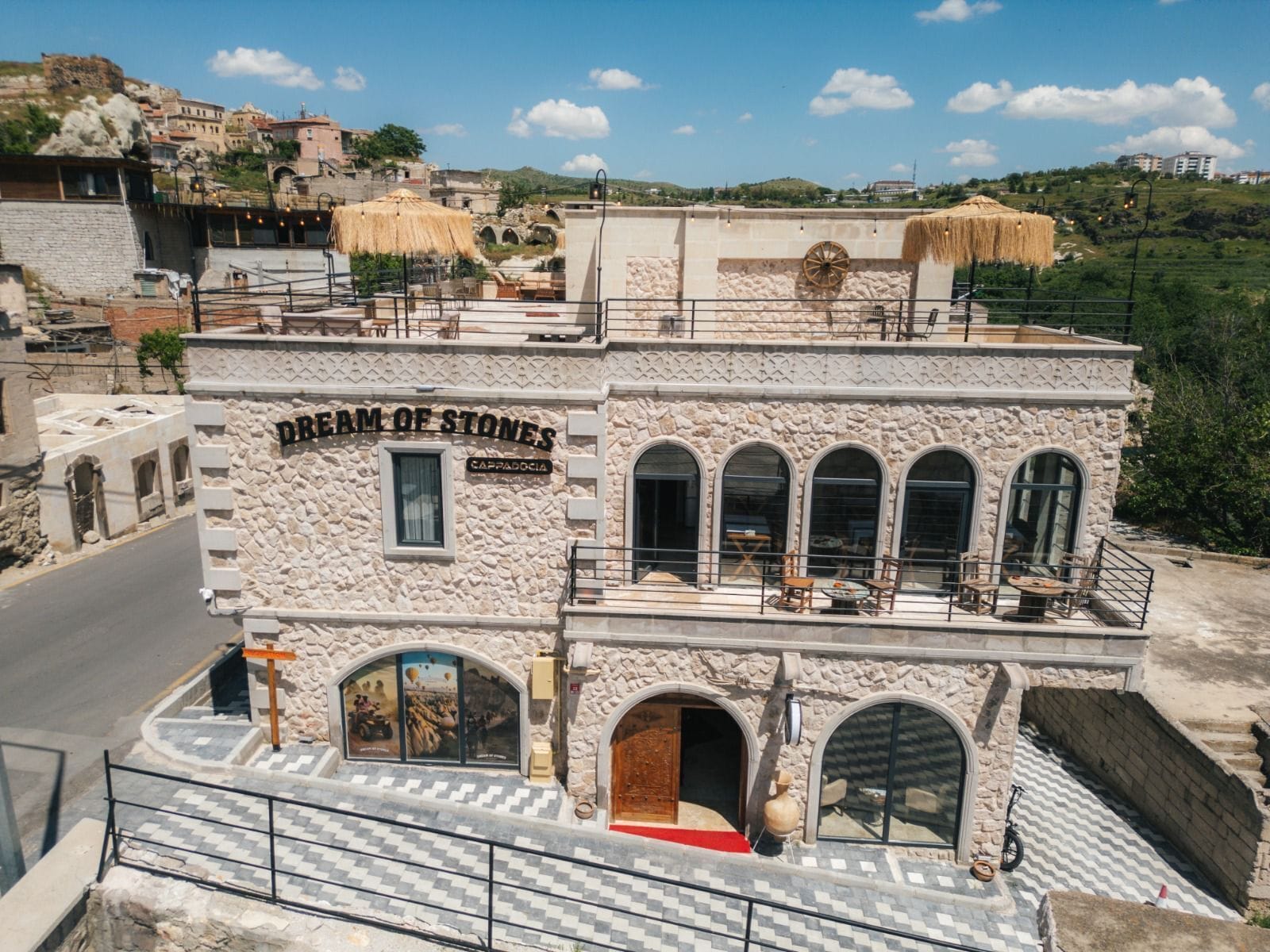 A stone building with a sign reading 'Dream of Stones.' It features arched windows and a balcony with outdoor seating.