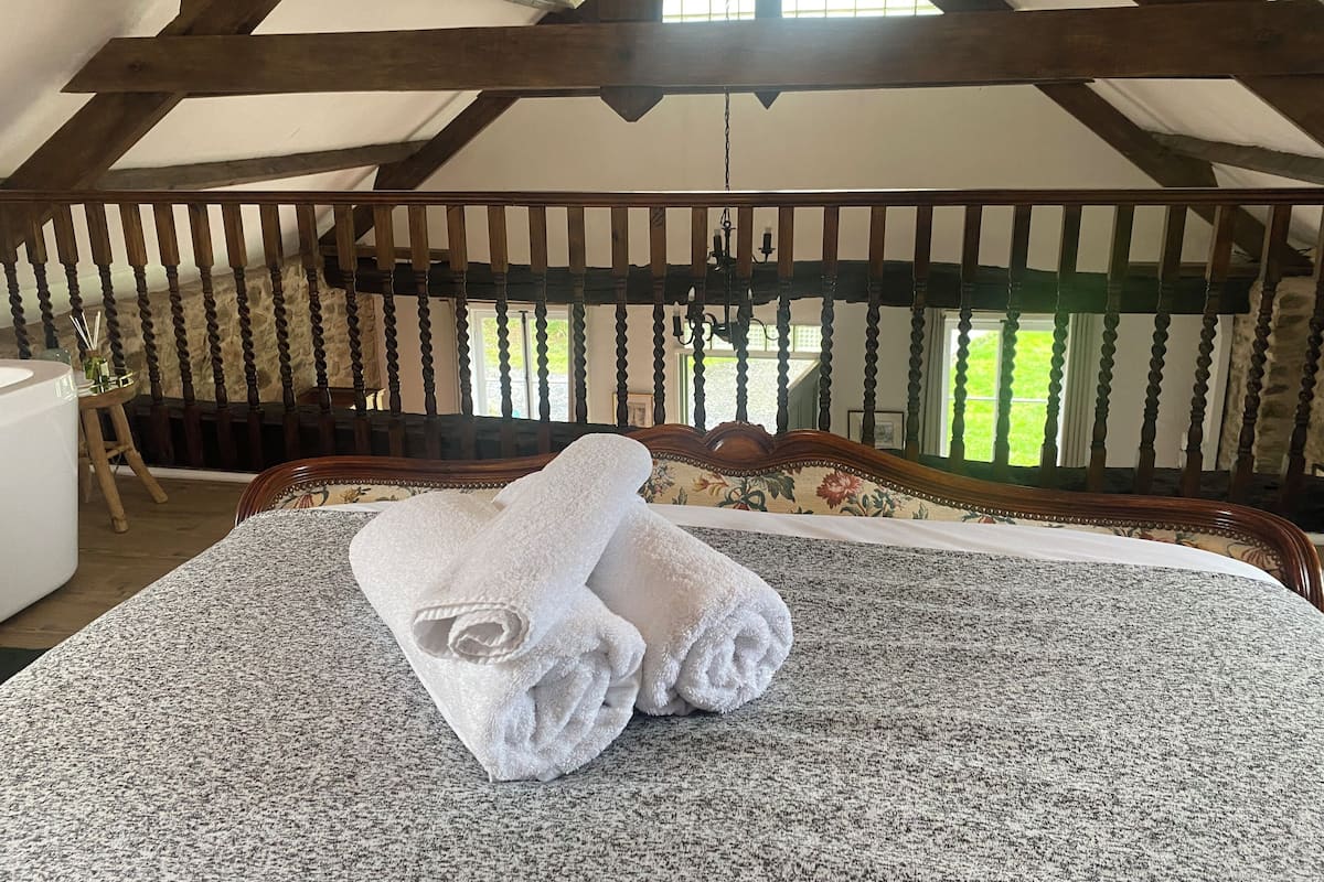 Une chambre avec un grand lit, des poutres en bois et une vue sur l’extérieur.