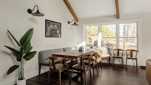 A dining area with a long wooden table, several chairs, a bench, and a potted plant.