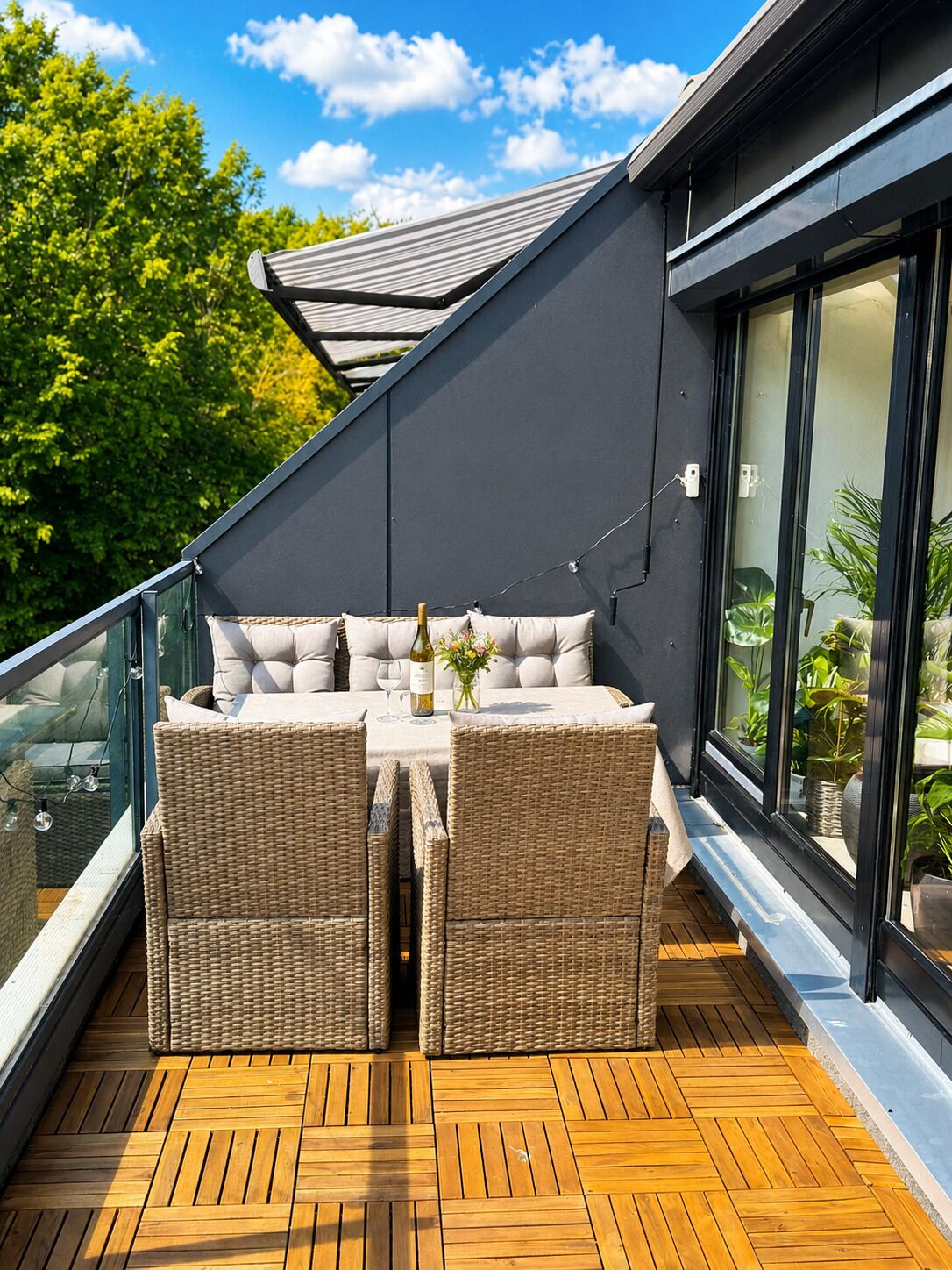 En balkon med sofaarrangement, bord og plantekasser.
