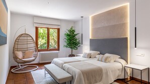 A modern bedroom with two beds, a hanging chair, a potted plant, and a large window. - Brisa (Son Servera)