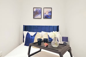 Una camera da letto con un letto, un comodino, una lampada e due opere d'arte appese al muro.