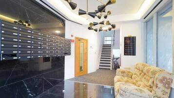A lobby with a black marble floor, a floral sofa, a staircase, and a wall-mounted mailbox.
