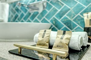 A bathroom with a sink, a towel rack with towels, and a shower cap on the counter. - Alaya Stays Casa Avakasha 4 BHK Villa  (Gurugram)