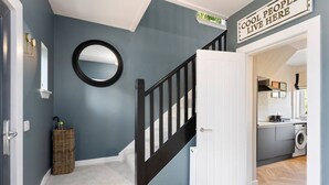 A hallway with a staircase, a mirror, a basket, and a sign that says "Cool People Live Here". - Paradykes House - Free Parking & Garden (Midlothian)