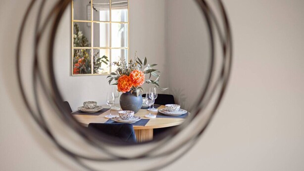 A dining table with plates, glasses, and a vase of flowers, viewed through a circular mirror. - Paradykes House - Free Parking & Garden (Midlothian)